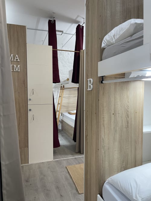 Dormitorio compartido en Therma Pilgrim Hostel con literas, cortinas divisoras y tabiques de madera en Caldas de Reis