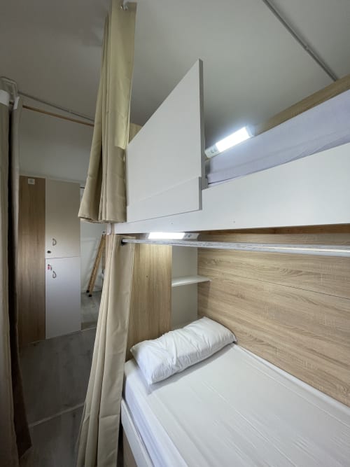 Litera con ropa blanca en habitación compartida de Therma Pilgrim Hostel, Caldas de Reis, con detalles de madera e iluminación LED