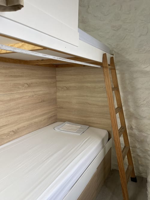 Litera de hostal con escalera de madera y ropa blanca en dormitorio compartido del Hostel Terma Peregrino, Caldas de Reis
