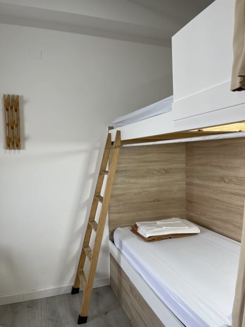 Litera moderna con escalera de madera y ropa de cama blanca en habitación compartida del Therma Pilgrim Hostel en Caldas de Reis