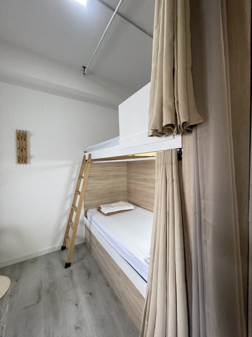 Acogedora litera con escalera de madera y cortinas beige en habitación compartida del Hostal Therma Pilgrim, Caldas de Reis
