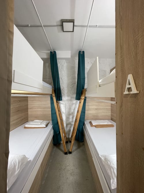 Cabaña dormitorio compartido de cuatro camas en Therma Pilgrim Hostel en Caldas de Reis con literas, cortinas verdes y detalles de madera