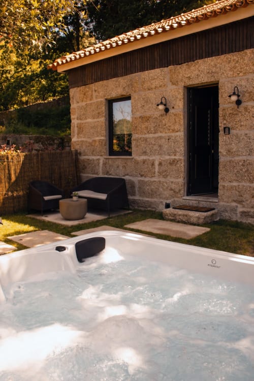 Villa Quinta Das Pirâmides Casa do Feitor com banheira de hidromassagem, pátio com assentos e arquitetura em pedra em Vila Nova de Famalicão