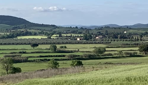 Paesaggio della campagna toscana con campi verdi ondulati e villaggi distanti vicino a Capalbio