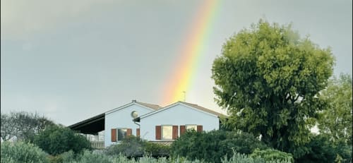 Casale Artemisia B&B en Capalbio con arcoíris sobre masía blanca y árboles verdes