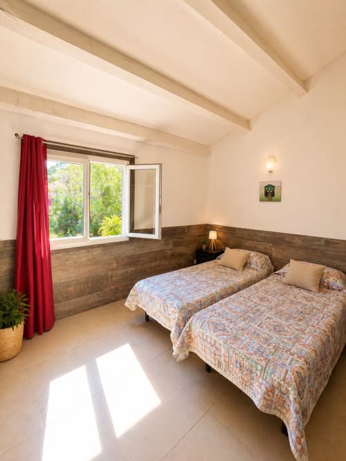 Camera twin all'hotel Le Maquis Plage a Poggio-Mezzana con rivestimenti in legno, tende rosse e vista sul giardino