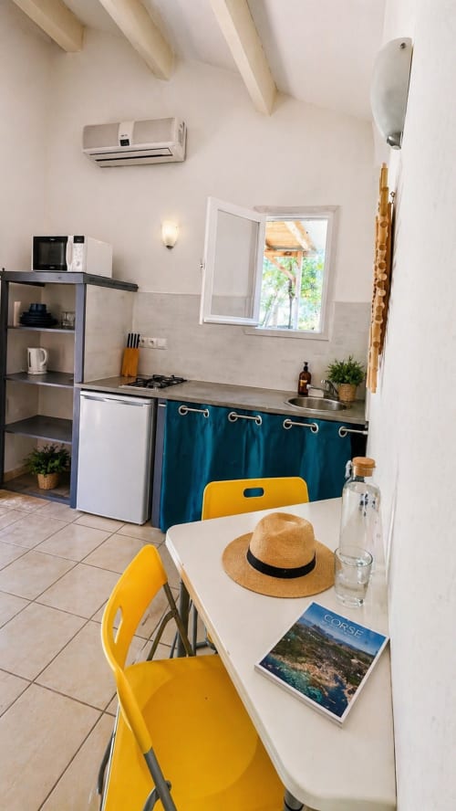 Piccola cucina moderna a Le Maquis Plage con sedie gialle, arredamento teal e tavolo da pranzo a Poggio-Mezzana