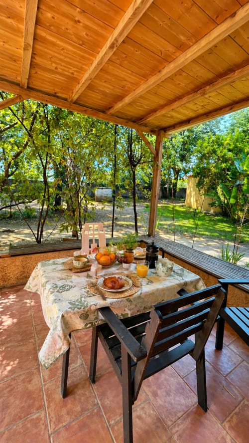 Pergolato coperto a Le Maquis Plage con tavolo apparecchiato per colazione, vista sul giardino