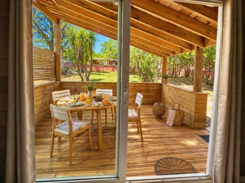 Le Maquis Plage wooden deck dining area with table and chairs overlooking tropical garden in Poggio-Mezzana
