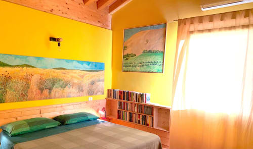 Dormitorio amarillo brillante con vigas de madera, obras de arte, almohadas verdes, estantería de CDs y suelos de terracota en Casale