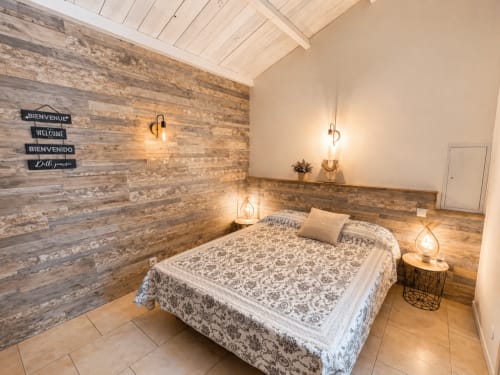 Chambre confortable de la villa Le Maquis Plage à Poggio-Mezzana avec mur d'accent en bois et éclairage ambiant