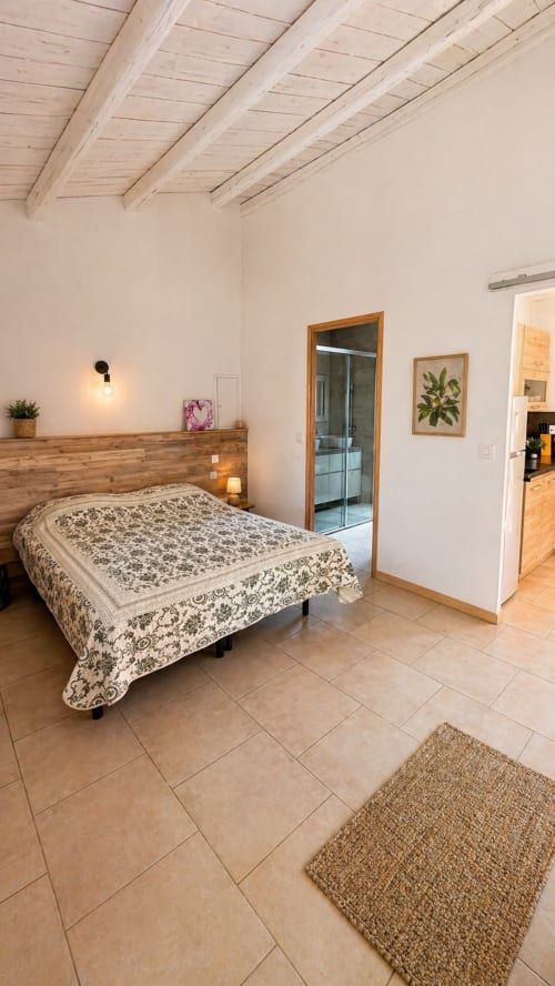 Chambre spacieuse à la villa Le Maquis Plage avec poutres en bois, couvre-lit à motifs, salle de bains privative et équipements modernes