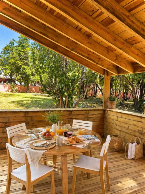 Pergola en bois avec coin repas à la villa Le Maquis Plage, petit-déjeuner servi et vue sur le jardin à Poggio-Mezzana