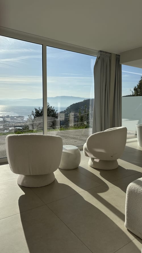 Modern lounge area at Otantus Maritimus hotel in Muros with cream chairs overlooking coastal bay views and mountains