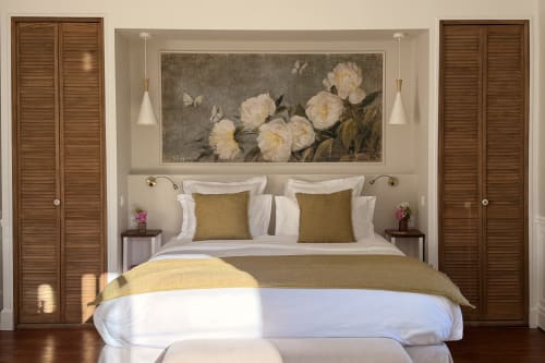 Chambre élégante à La Maison 1680 avec literie blanche, oreillers olive et tableaux de pivoines au-dessus du lit