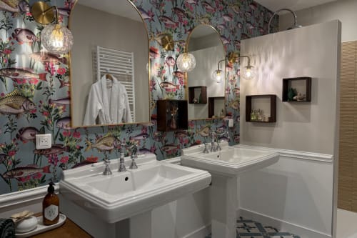 Luxury bathroom at La Maison 1680 B&B with dual sinks, floral wallpaper, brass mirrors and pendant lights in Couches, France