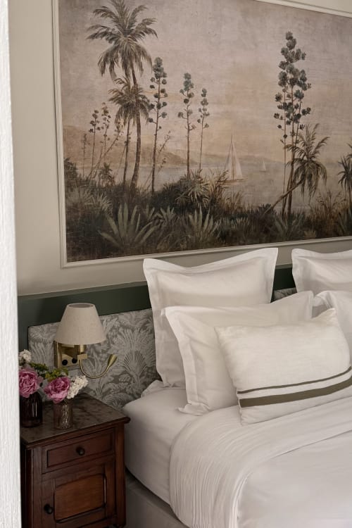 Elegant bedroom at La Maison 1680 in Couches with white bedding, wood nightstand, brass lamp, pink flowers, and botanical
