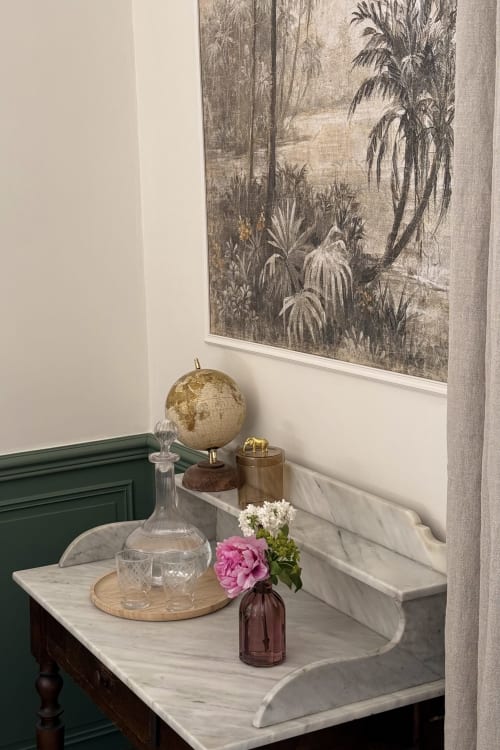 La chambre de Jeanne room vignette at La Maison 1680 with marble table, pink flowers, and vintage botanical artwork
