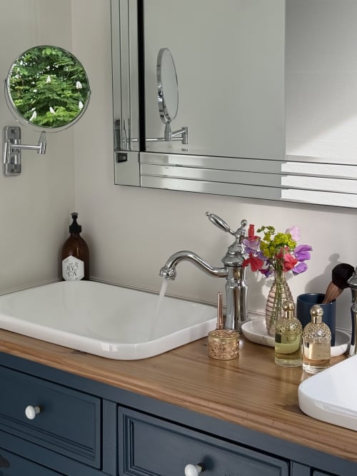 Elegant dual-sink bathroom at La Maison 1680 with chrome fixtures, fresh flowers, and luxury toiletries