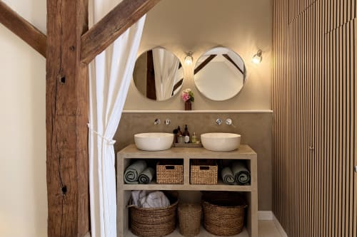 Modern bathroom at La Maison 1680 B&B in Couches with dual vessel sinks, round mirrors, and rustic wooden beams