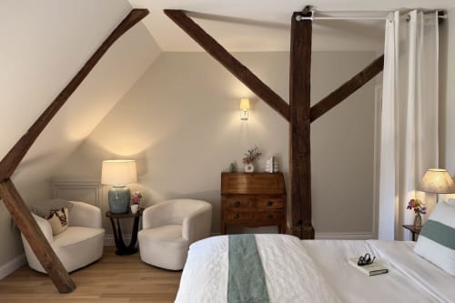 La Maison 1680 bedroom with exposed wooden beams, elegant furnishings, and garden views