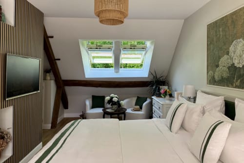 Elegant attic bedroom with cream bedding, skylight windows, dark wood beams, and garden view at La Maison 1680 in Couches,