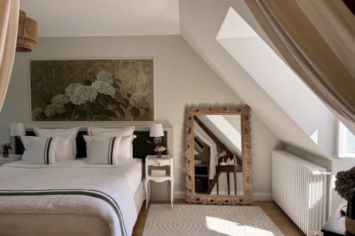 Bright attic bedroom at La Maison 1680 with white bedding, ornate mirror, garden view, and skylights