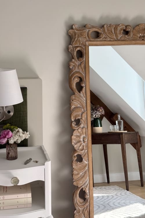 Ornate wooden mirror frame in La chambre de Joseph at La Maison 1680 B&B, Couches, reflecting bedroom with desk and flowers