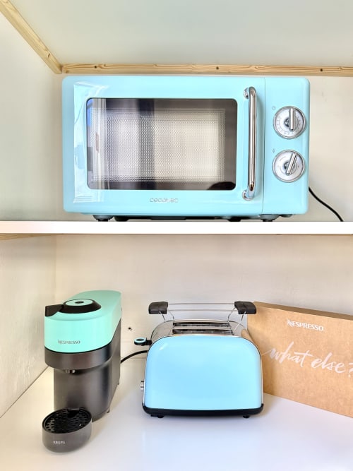 Petits appareils de cuisine rétro bleu clair sur étagères en bois à l'auberge Nanit Rooms Ibiza : micro-ondes, cafetière et grille-pain