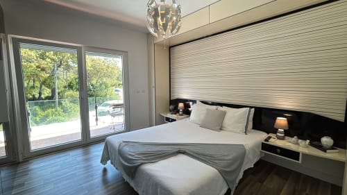Quarto moderno da villa Casa Cliff com vista para a piscina, cama queen-size, portas de vidro para a varanda, móveis contemporâneos e luz natural