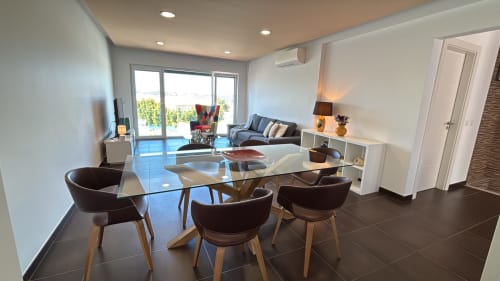 Sala de estar de villa moderna em Sesimbra Sun Sea com mesa de jantar de vidro, cadeiras escuras, sofá, vista da piscina pelas portas do terraço