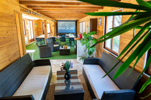 Élégant salon en bois à Domaine Sur-Valot avec sièges confortables, plantes et lumière naturelle