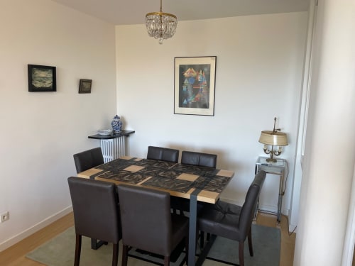 Modern dining room with black leather chairs, wooden table, crystal chandelier, and framed artwork in Saint Raphaël apartment