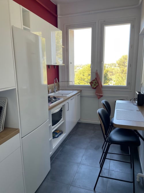 Modern apartment kitchen with white cabinets, dining area, and sea view windows at Résidence Le Château Du Parc Santa Lucia,