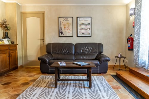 Salon moderne avec canapé en cuir noir, table en bois et tapis à motifs au Gîte Le Souvigne, Domaine Sur-Valot, Beaubery