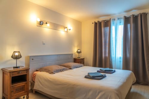 Chambre lumineuse au Gîte La Combe à Beaubery avec lit queen-size, vue sur le jardin et éclairage chaleureux.