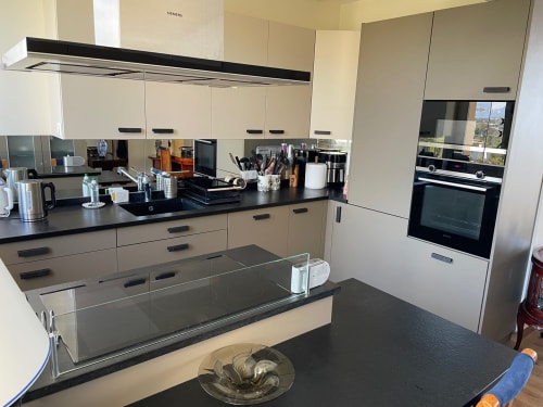 Modern kitchen in Résidence Le Château Du Parc Santa Lucia apartment with cream cabinetry, black countertops, and built-in