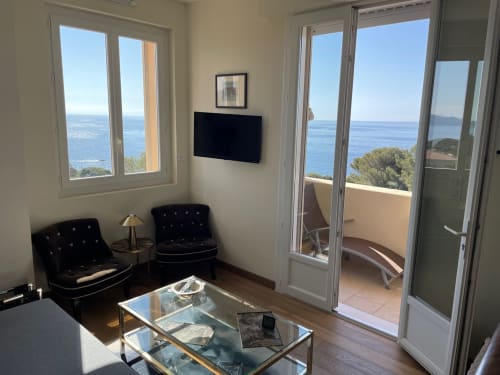 Bright apartment living room with sea views in Saint Raphaël, black chairs, glass table, and access to balcony overlooking