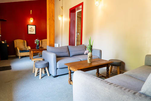 Spacieux salon du gîte Domaine Sur-Valot avec canapé bleu, table en bois et mur d'accent rouge
