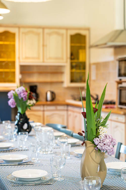 Élégante salle à manger au Domaine Sur-Valot avec centre de table floral, table dressée et armoires de cuisine modernes