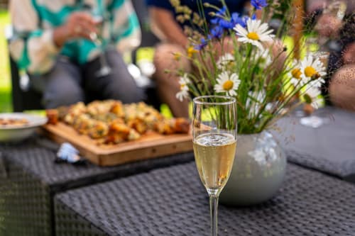 Verre de champagne à table en jardin, Domaine Sur-Valot, entouré de fleurs fraîches et d'amuse-bouches à Beaubery
