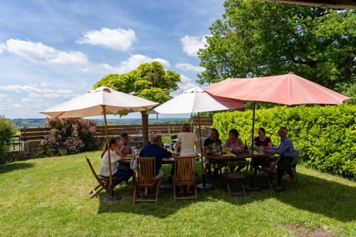 Des invités dînent en plein air sous des parasols dans le jardin du Domaine Sur-Valot à Beaubery, France