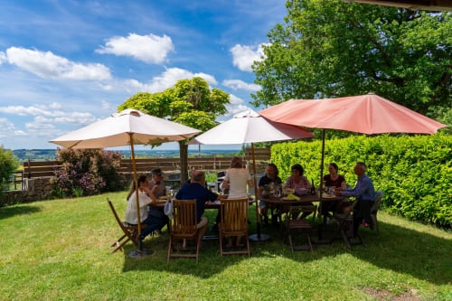 Repas en groupe sous parasols au Domaine Sur-Valot, Beaubery, avec vue sur la campagne environnante