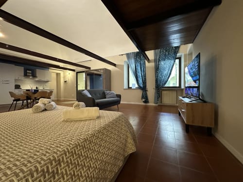 Spacious loft bedroom at Cinelli Apartment in Vercelli with bed, sofa, TV, kitchen, and modern amenities