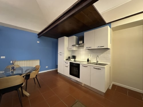 Modern kitchen with white cabinets and dining area in Cinelli Apartment loft, Vercelli, featuring blue accent wall and