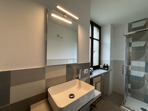 Modern bathroom in Cinelli Apartment, Vercelli with vessel sink, illuminated mirror, and walk-in shower