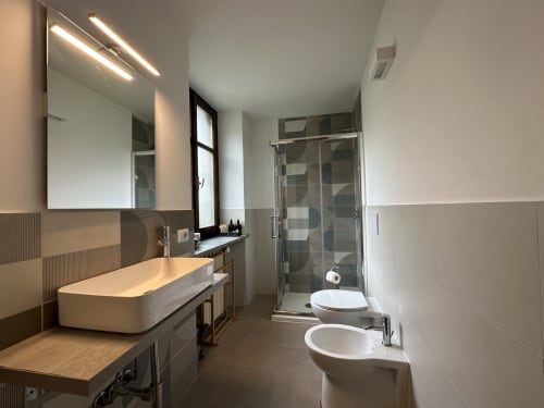 Modern bathroom in Cinelli Apartment Vercelli with double sink, illuminated mirror, glass shower enclosure, and bidet