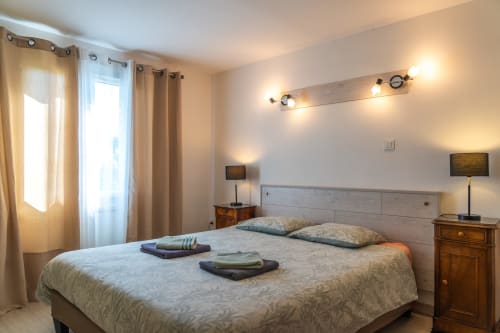 Chambre lumineuse avec lit queen, tables de nuit en bois et éclairage moderne au gîte Domaine Sur-Valot à Beaubery