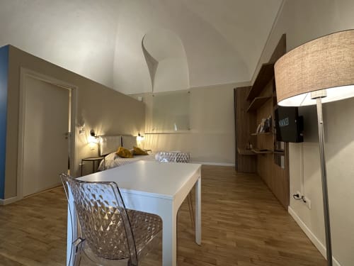 Modern loft apartment at Cinelli Apartment, Vercelli - open-plan living with white dining table, bed, wood furniture and
