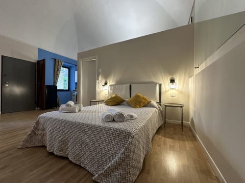 Modern loft bedroom at Cinelli Apartment in Vercelli with queen bed, gold pillows, and garden views